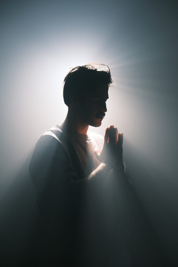 prayer, gratitude, hope, enlightenment, silhouette, dramatic lighting, shadow, cinematic, conceptual, meditation, peaceful, spiritual, introspective, divine light, mysticism, halo effect, mindfulness, expressive, emotional, soft glow, light rays, meditative pose, tranquility